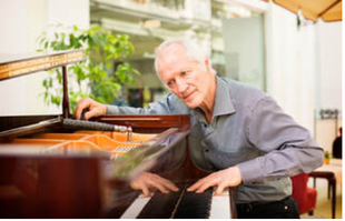 Picture of an elderly piano technician tuning a grand piano