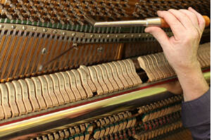 Picture of a man's hand tuning an old piano