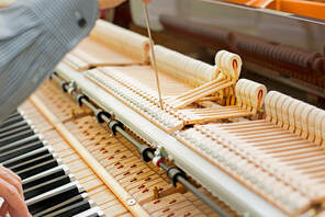 Picture of a man repairing the hammer mechanism of a piano