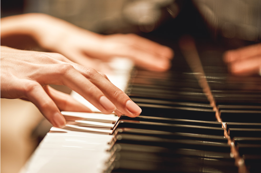 A zoomed in picture of a woman's hands playing a piano